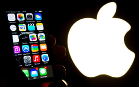 This file photo taken on January 30, 2015 shows a hand holding an iphone next to the Apple logo in Lille.