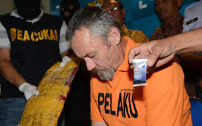 Antony de Malmanche of New Zealand sits as evidence is placed next to him during a press conference in Denpasar, Bali.