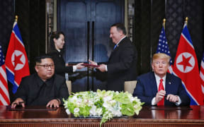 US President Donald Trump and North Korea's leader Kim Jong Un participate in a signing ceremony as part of the US-North Korea summit, at the Capella Hotel on Sentosa Island in Singapore on June 12, 2018.