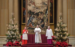 This handout photo taken on December 25, 2020, and released by the Vatican press office, the Vatican Media, shows Pope Francis (C) delivering his streamed Urbi et Orbi blessing from the Vatican Blessing hall.