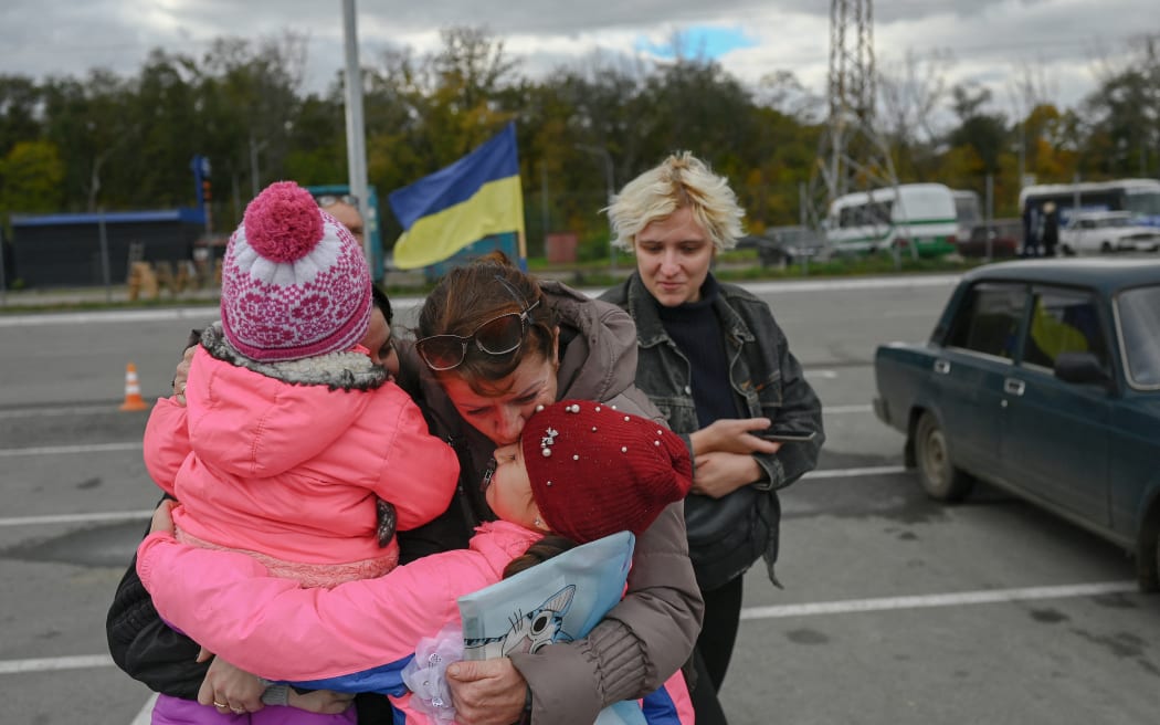 A Ukrainian woman and her children are welcomed by a relative after they were able to leave from Russian occupied territory of Kherson, in Zaporizhzhia, on 21 October, 2022, amid Russia's invasion on Ukraine.