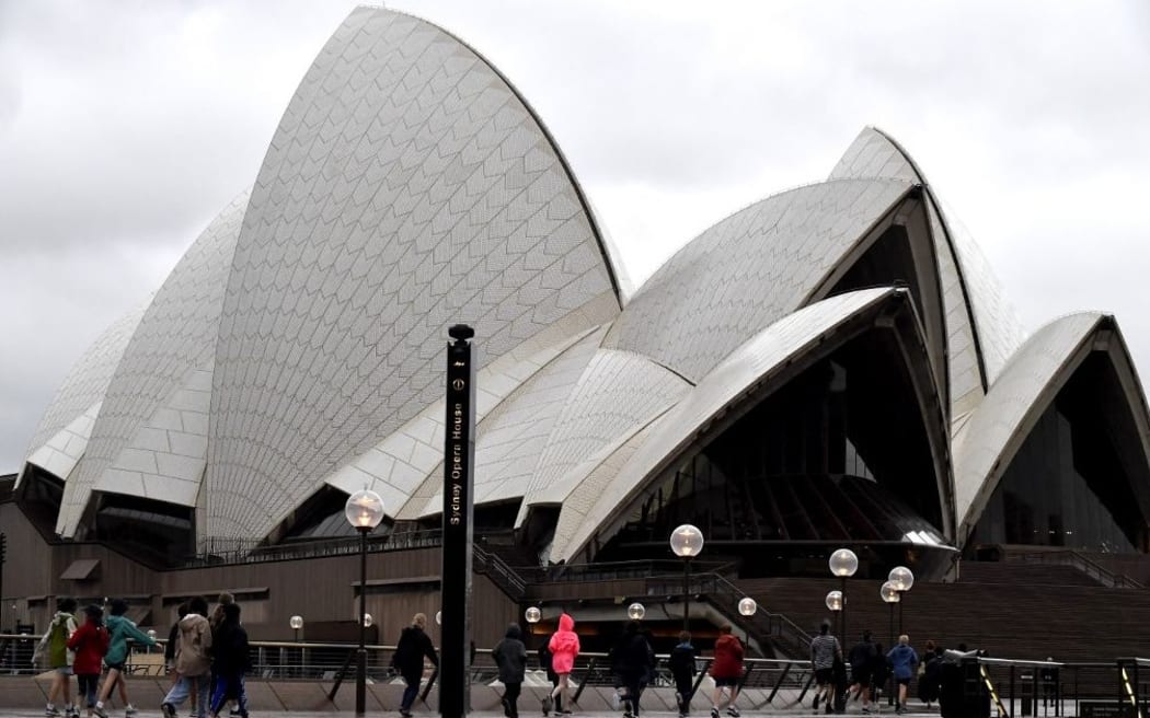 People visit Opera House in Sydney on March 8, 2022, amid the national weather bureau's warning of "a tough 48 hours ahead", with 60,000 people subject to evacuation orders and warnings across affected areas. (Photo by Muhammad FAROOQ / AFP)