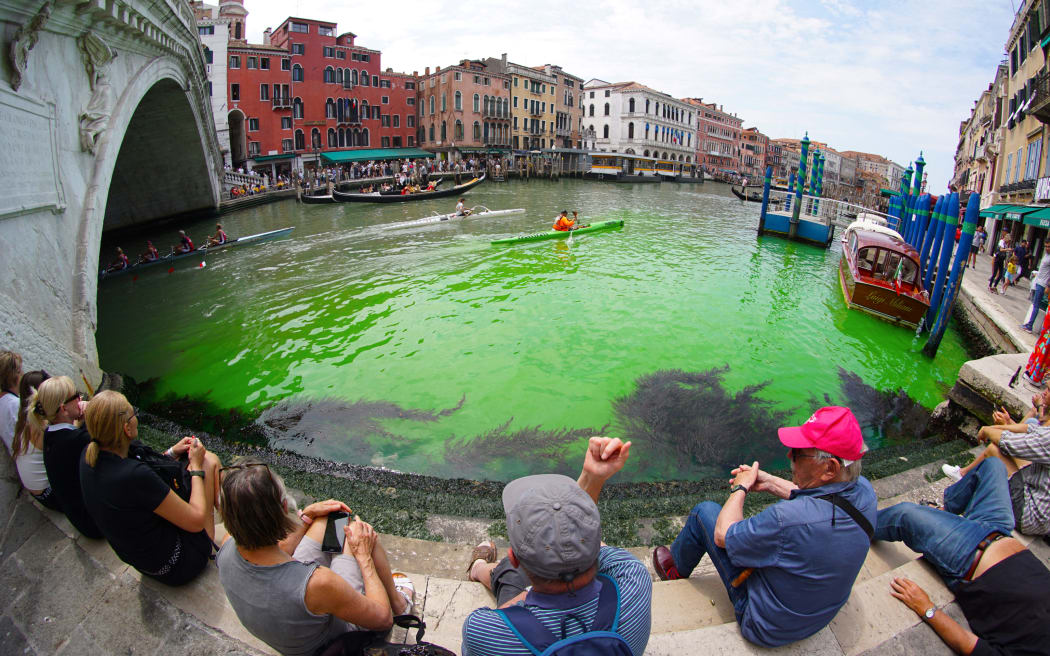 A photo taken and made available on May 28, 2023 by Italian news agency Ansa, shows fluorescent green waters below the Rialto Bridge in Venice's Grand Canal.