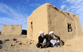 Afghan residents sit outside a hut on the outskirts of Herat.