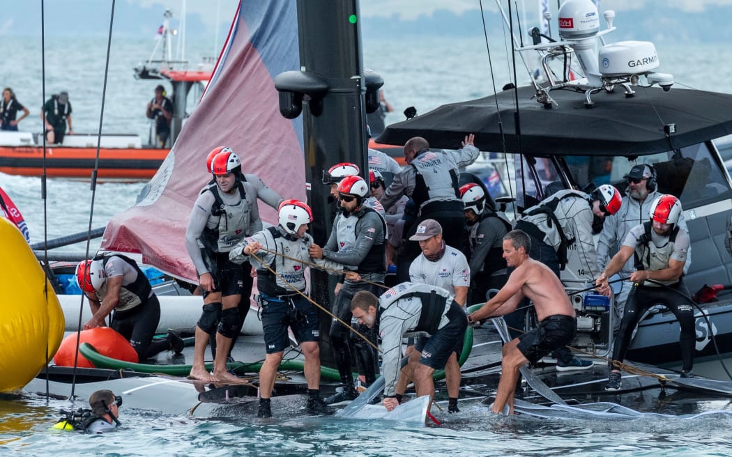 Emirates Team New Zealand sailor Richard Meacham (shirtless) assists with the recovery of Patriot after American Magic capsize in their Round Robin 2 match against Luna Rossa Prada Pirelli Team. Prada Cup. Sunday 17th of January 2021.
