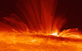 Sunspot with streamers of super-hot, electrically charged gas (plasma) arc from the surface of the Sun, revealing the structure of the solar magnetic field.