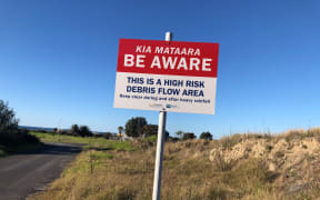 Sign at coastal settlement of Matatā warning people that it is a high risk debris flow area.
