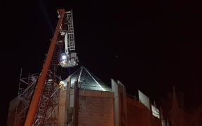 A crane above the roof of St Paul's Cathedral in Dunedin where firefighters are working to put out a fire in the roof.