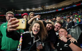 New Zealand loosehead prop Ethan de Groot (R) poses for selfie photos after winning the quarter-final Rugby World Cup 2023 match between Ireland and New Zealand at the Stade de France.