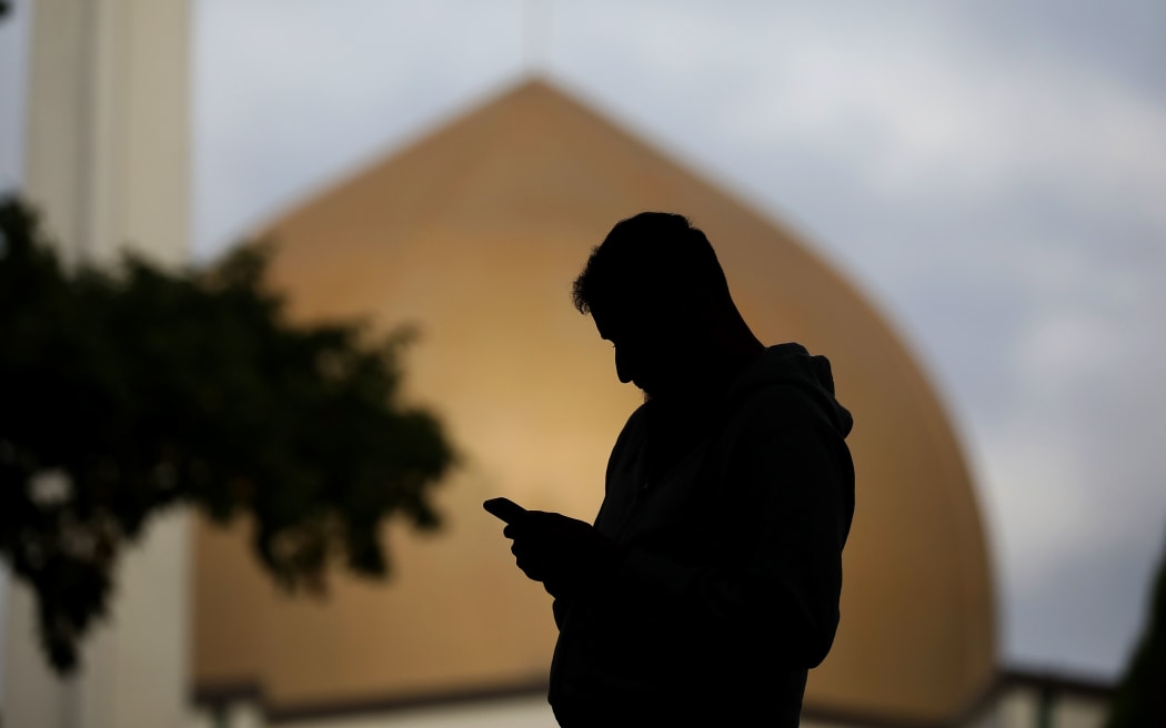 A member of the Muslim community uses his mobile phone out side the Al Noor mosque in Christchurch, New Zealand on March 15, 2020.