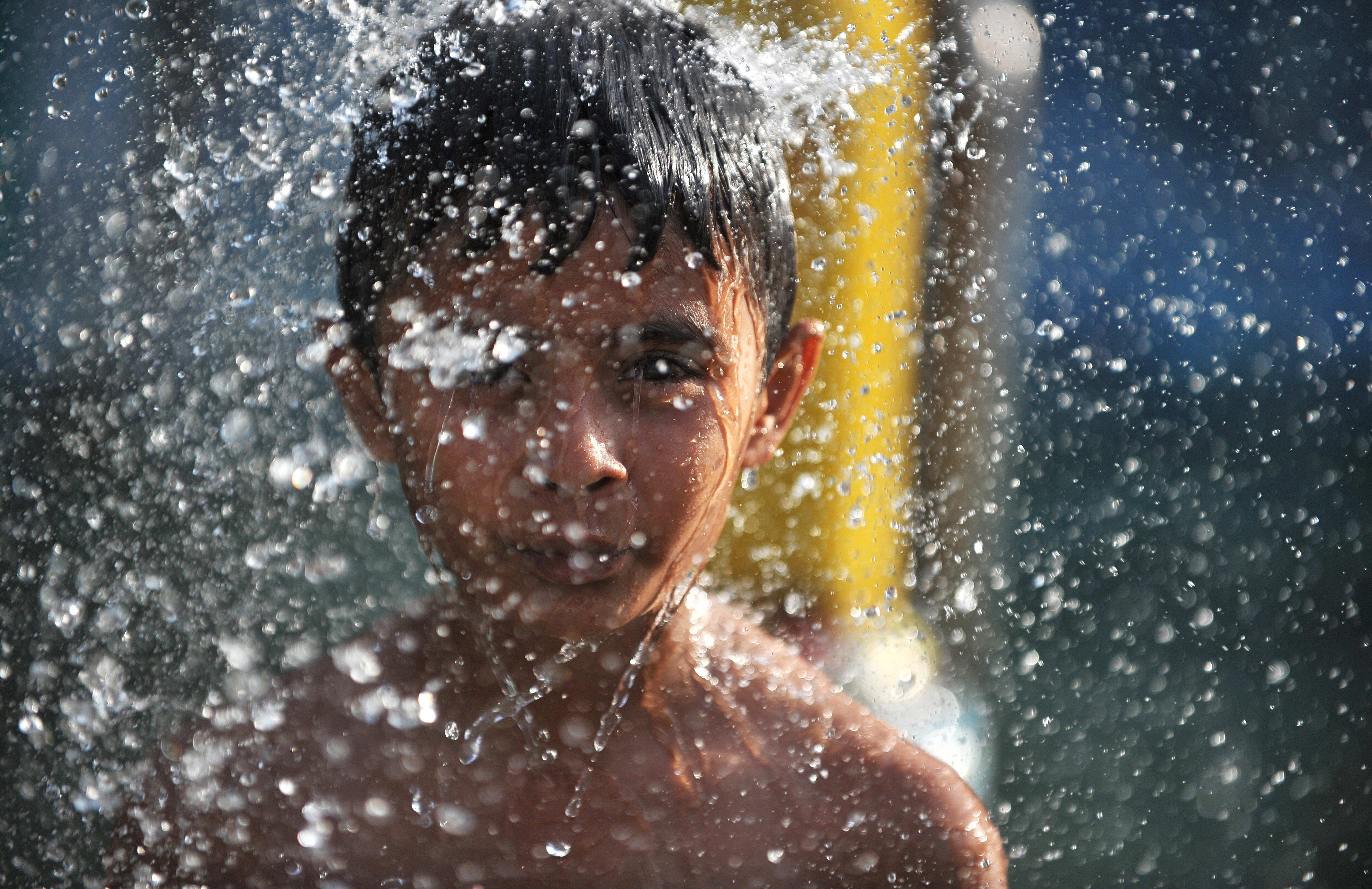 An Indian child cools off under a fountain at a water park in Hyderabad