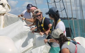 An image of several SEA students working together to fold a sail.