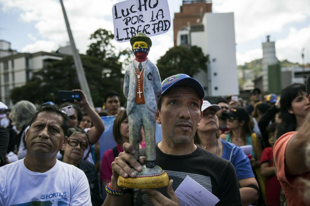 A man holds a statuette of Venezuelan popular saint and  a sign that reads "I fight for liberty," as members of the opposition gather to propose amnesty laws for the police and the military, in Caracas, Venezuela