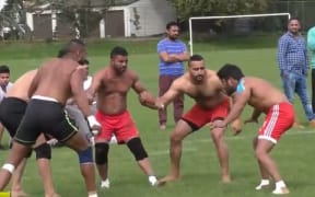 Men with shirts off and sports shorts watchfully in a circle as part of the Indian sport Kabbadi