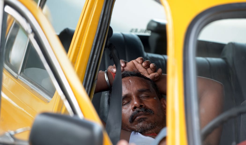 An Indian taxi driver rests in his parked car in Kolkata on 25 May 2015.