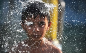 An Indian child cools off under a fountain at a water park in Hyderabad