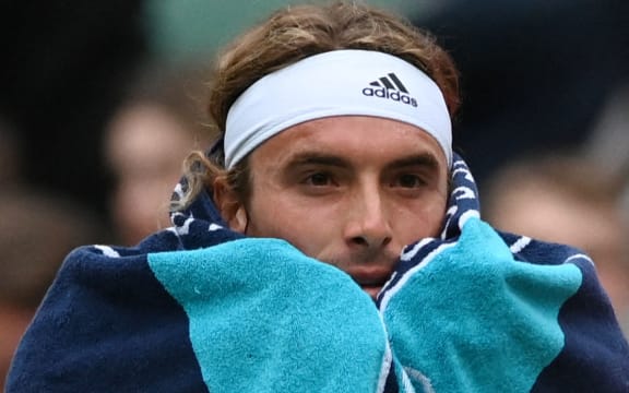 Grecki Stefanos Tsitsipas owija się ręcznikiem podczas przerwy w tenisowym pojedynku mężczyzn z Australijczykiem Nickiem Kyrgiosem w szóstym dniu Mistrzostw Wimbledonu 2022 w All England Tennis Club w Wimbledonie w południowo-zachodnim Londynie 2 lipca 2022 r.  (Zdjęcie: Glyn KIRK / AFP) / OGRANICZONE DO UŻYTKU REDAKCYJNEGO