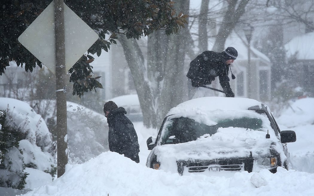 Arlington, Virginia, residents clear snow from their car.