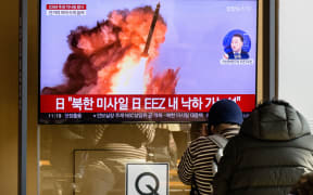 People sit near a television showing a news broadcast with file footage of a North Korean missile test, at a railway station in Seoul on November 18, 2022. - A suspected intercontinental ballistic missile launched by North Korea on Friday is believed to have fallen in Japan's exclusive economic waters, Japanese Prime Minister Fumio Kishida said. (Photo by Anthony WALLACE / AFP)