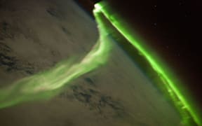 A green Aurora Australis snaking across cloud