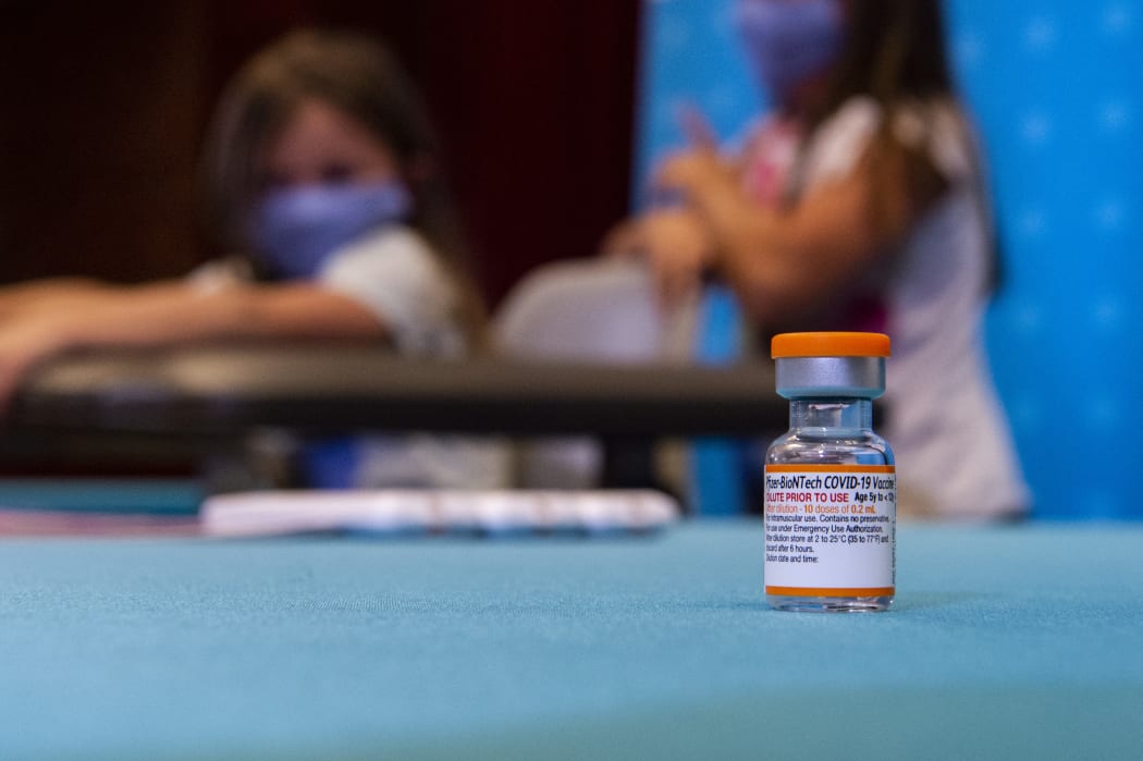 A vial of the new children's dose of the Pfizer-BioNTech Covid-19 vaccine sits in the foreground as children play in a hospital room at Hartford Hospital, Connecticut, US, 2 November 2021.