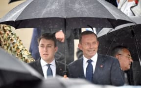 Former Australian prime minister Tony Abbott (R) and a former staffer attend a remembrance service attended by Britain's Prince Charles and Camilla, Duchess of Cambridge at the Australian War Memorial in Canberra on November 11, 2015