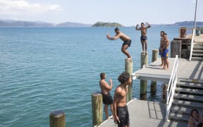 A group of teenagers and kids cooling off at Petone Wharf.