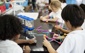 Diverse kindergarten students holding learning structures from toys