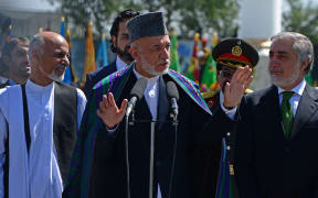 Afghan President Hamid Karzai (C) gestures while speaking as presidential candidates Ashraf Ghani (L) and Abdullah Abdullah (R) look on during an event to mark Independence Day at the Ministry of Defence compound in Kabul on August 19, 2014.