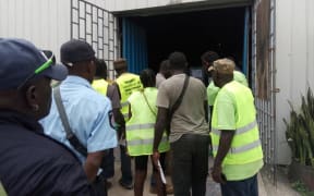 Observers and staff watch the transportation of ballot boxes