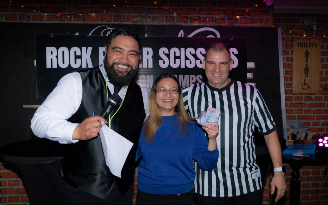 The winner of Wellington's Rock Paper Scissors Championship at The Residence bar, Zoe Rivera (C) poses with her cash prize.