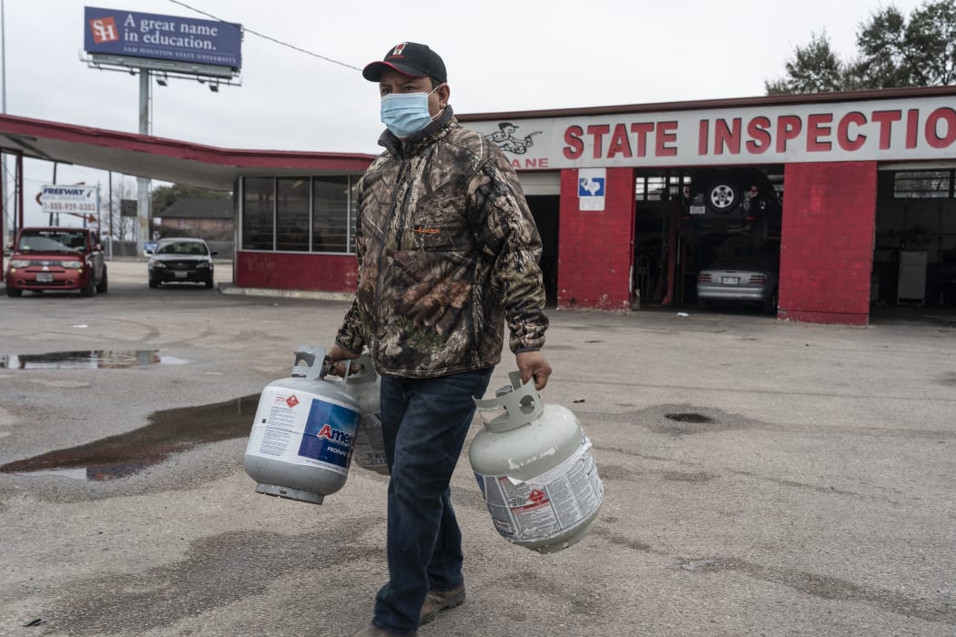 A man brings propane tanks to refill at a propane gas station after a winter freeze caused electricity blackouts in Houston, Texas, 18 February 2021