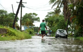 Residents wade through the flooded streets in Fiji's capital city of Suva on December 16, 2020, ahead of super Cyclone Yasa.