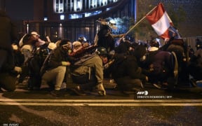 Demonstrators, supporters of Peruvian ousted President Martin Vizcarra, holding a Peruvian flag, clash with riot ppolice during a protest against the government of interim president Manuel Merino.