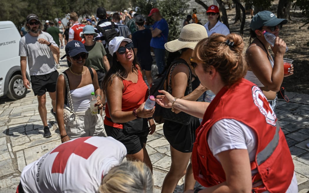 Hellenic Red Cross workers distribute bottles of water to visitors outside the Acropolis in Athens on 13 July, 2023, as Greece hits high temperatures.