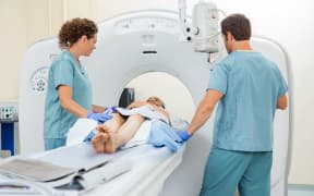 A nurse prepares a woman for a CT scan.