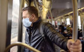A man wearing a disposable medical face mask in car of a subway in New York during coronavirus outbreak.