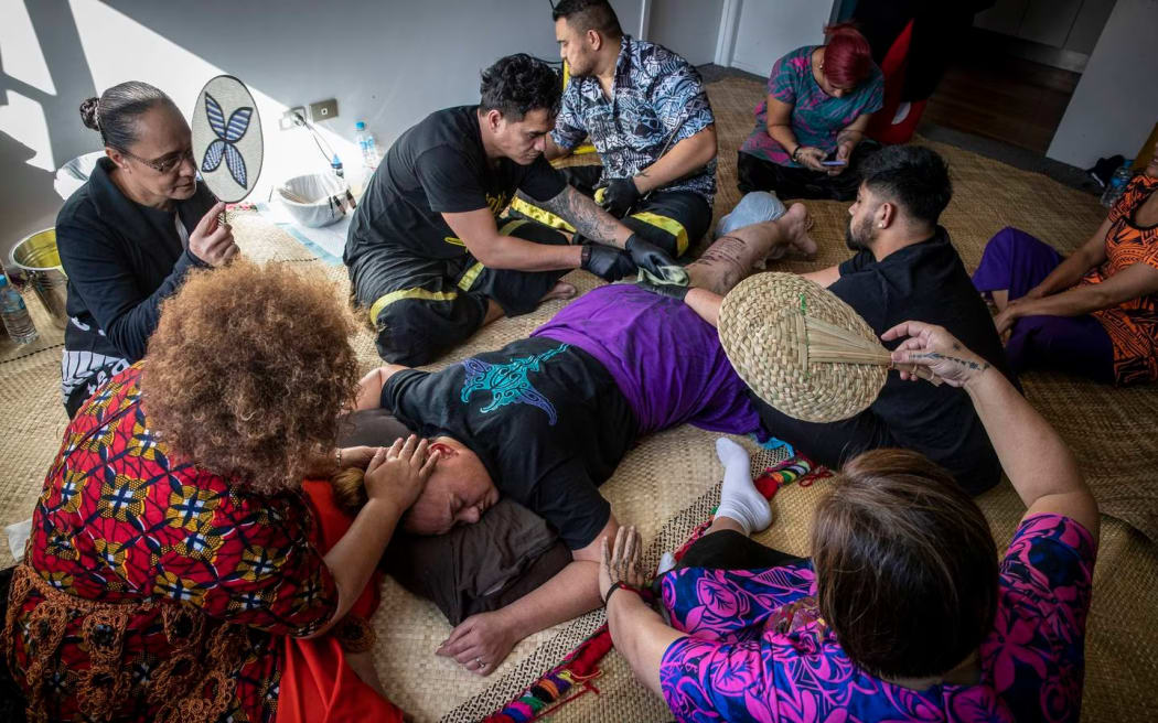 Deputy PM Carmel Sepuloni is supported by fellow MPs and family during her traditional tatau.