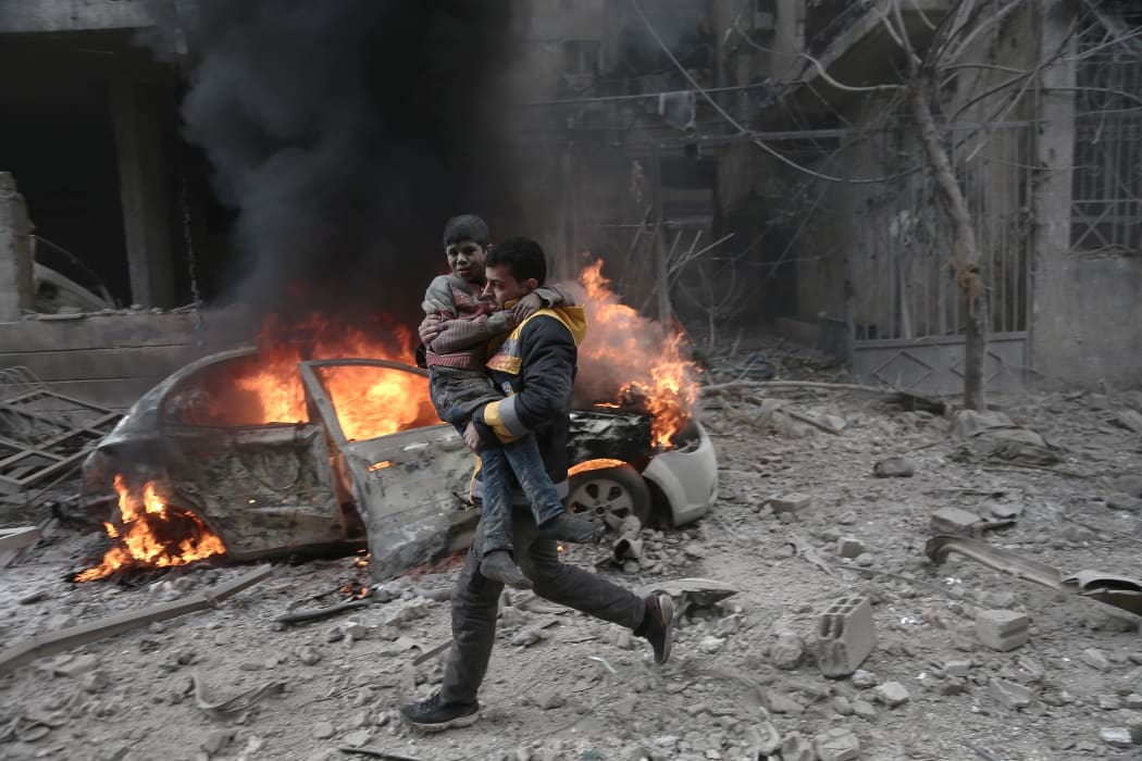 A Syrian paramedic carries an injured child following reported bombardment by Syrian and Russian forces in the rebel-held town of Hamouria, in the Eastern Ghouta.