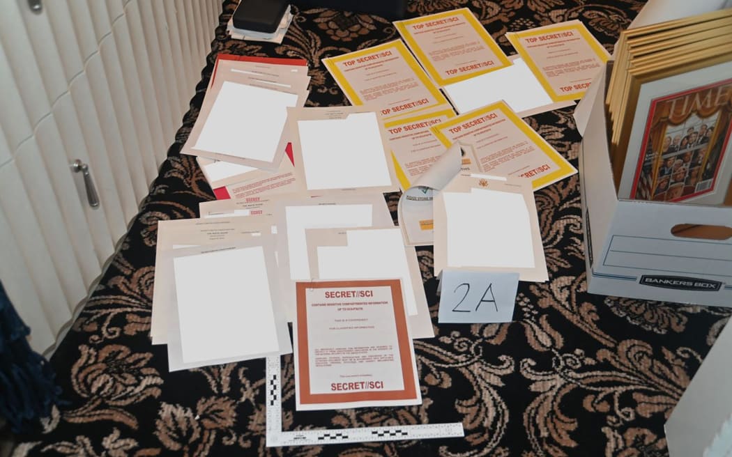 Una foto adjunta como evidencia a un Tribunal de Distrito de EE. UU. para el Distrito Sur de Florida demanda de documentos presuntamente incautados en Mar-a-Lago esparcidos sobre una alfombra.