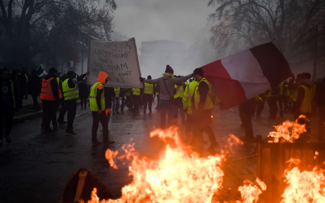 Demonstrators carry a French flag during a protest of Yellow vests (Gilets jaunes) against rising oil prices and living costs, on December 1, 2018 in Paris.
