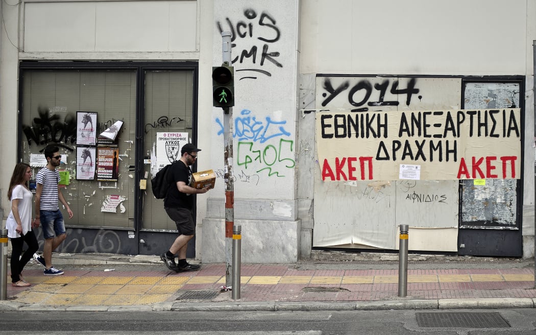 People walk past closed businesses in central Athens.