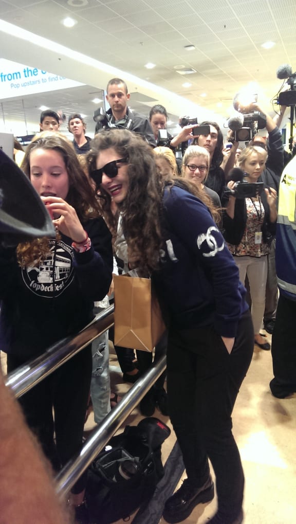 Fans swarm around Lorde as she arrives back in Auckland from the Grammys.