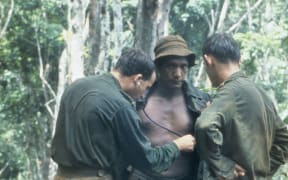 An Australian medical officer treating minor ailments of members of the New Zealand W Company during a resupply in the field during the Vietnam War.
