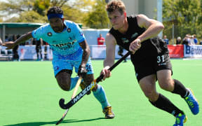 Steve Edwards of the Black Sticks is tackled by Birendra Lakra of India.