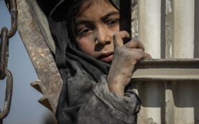 A girl looks out of one of the trucks in a convoy evacuating civilians and family members of Islamic State fighters from the last area held by the group to a temporary camp.