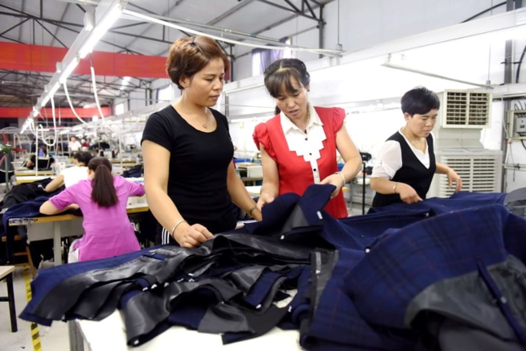 Bai Shuxiang (C) and Du Caizhi (L) from Qiandong Village of Nanhe County, north China's Hebei Province, examine products' quality at a local anti-poverty factory,