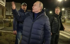 This handout video grab released by Russian Presidential Press Office on March 19, 2023, shows Russian President Vladimir Putin speaking with people at a newly built neighborhood during his visit to Mariupol in Russian-controlled Donetsk region.