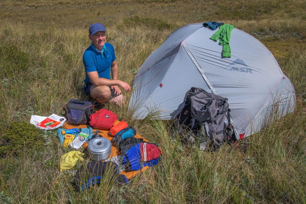 Tramper, writer and photographer Shaun Barnett with the gear he takes on a tramping trip.