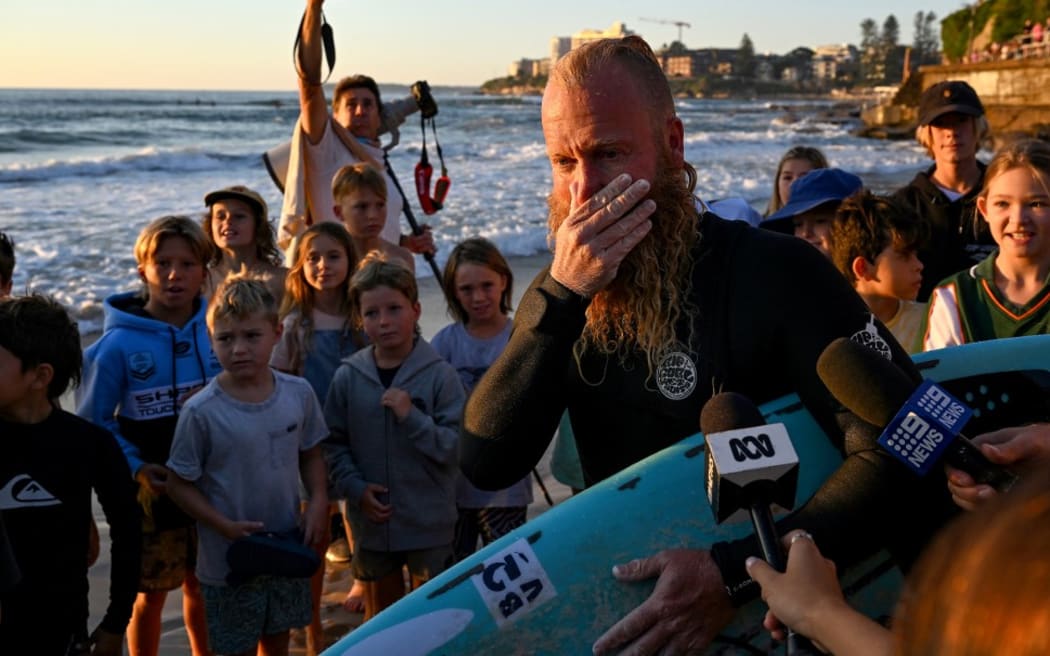 El ex surfista profesional australiano Blake Johnston habla con los medios de comunicación después de romper el récord de la sesión de surf más larga del mundo en Cronulla Beach en Sydney el 17 de marzo de 2023.  - El australiano Blake Johnston, viernes 17 de marzo de 2023, rompió el récord mundial de la sesión de surf consecutiva más larga, dijo que se sentía "muy bien cocinado" Después de coger olas durante más de 30 horas.  El ex surfista profesional de 40 años se echó a llorar después de romper el récord anterior de Josh Elsin de Sudáfrica de 30 horas y 11 minutos.  (Foto de Saeed Khan / AFP) / “False note[s] Los metadatos de esta foto de Saeed Khan aparecen en la configuración de AFP de la siguiente manera: [removes reference to spending 40 hours in the water].  Eliminar la nota errónea inmediatamente[s] De todos sus servicios en línea…